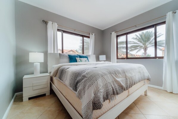 A bedroom with a bed, nightstands, and a window with curtains.