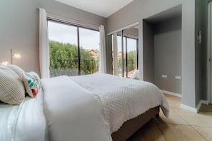 A bedroom with a large bed, a balcony, and a view of greenery and buildings. - Villa Diamante: Luxe Oasis, Gold Coast 4BR 3BA (Noord)