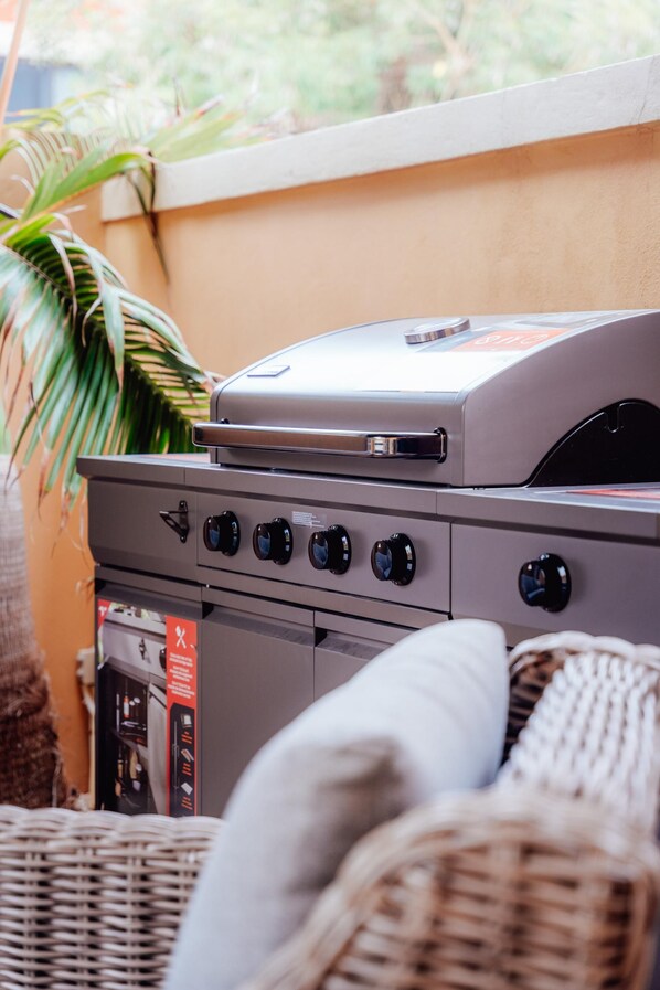 A barbecue grill with four control knobs, a digital display, and a side burner.