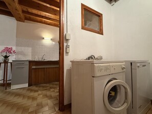 Ein Waschraum mit einer Waschmaschine, einem Trockner und einem kleinen Fenster.