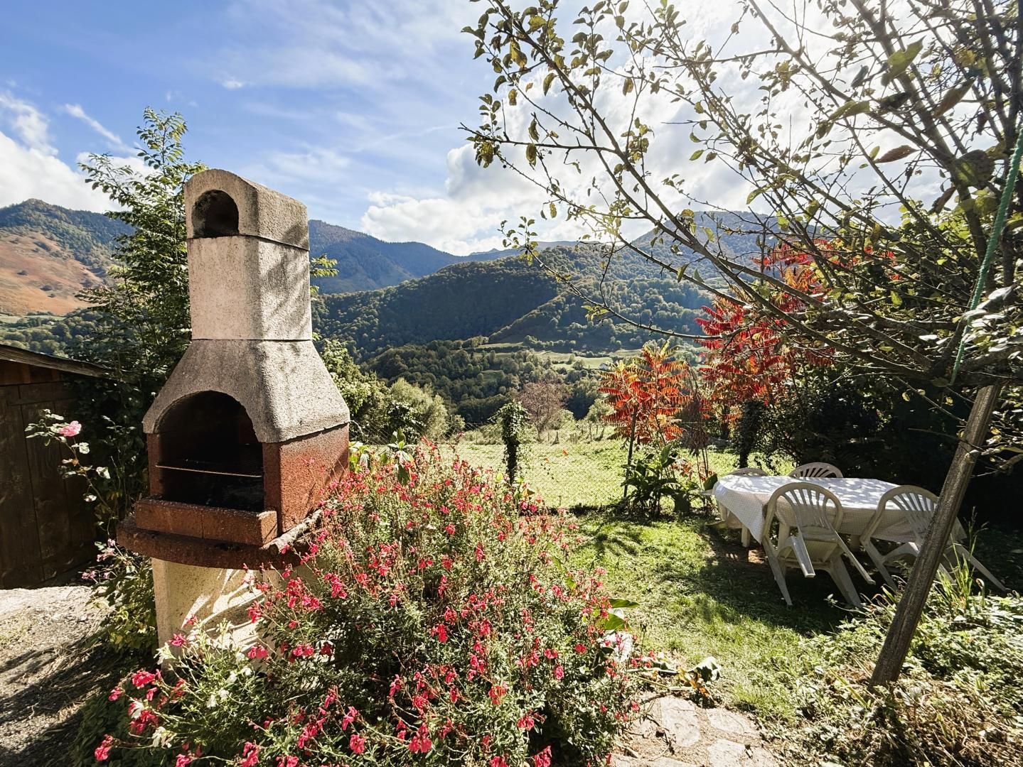 A stone oven structure in a garden with a view of mountains.