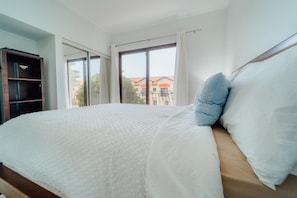 Ein Schlafzimmer mit einem großen Bett, einem Kleiderschrank und einem Balkon mit Blick auf Gebäude.
