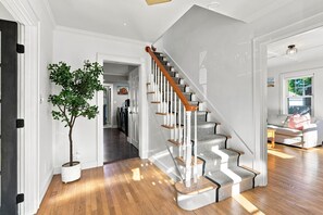A staircase with a wooden handrail and grey carpeted steps leading to a second floor. - Paws on Murphy - Near Beaches & Main Street (Hyannis)