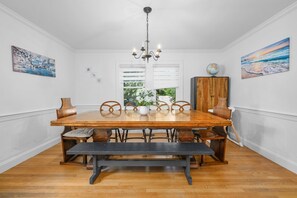 A dining room with a wooden table, benches, and a chandelier. - Paws on Murphy - Near Beaches & Main Street (Hyannis)