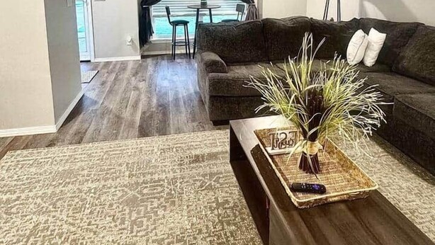 Sala de estar com sofá, mesa de centro e vista para o exterior.