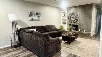 A modern living room with a sectional sofa, a coffee table, and a fireplace.
