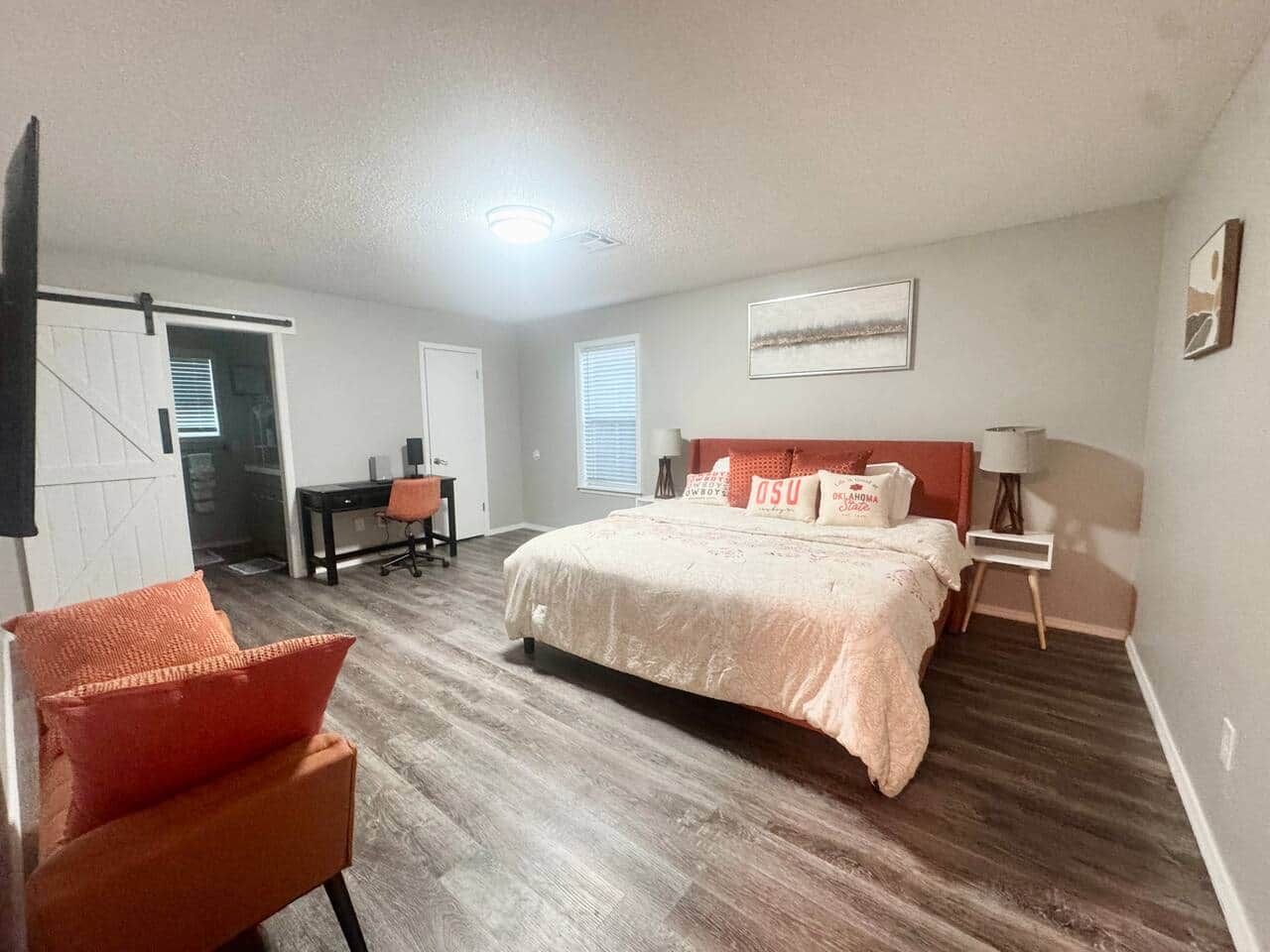 A bedroom with a bed, a desk, a chair, and a nightstand.