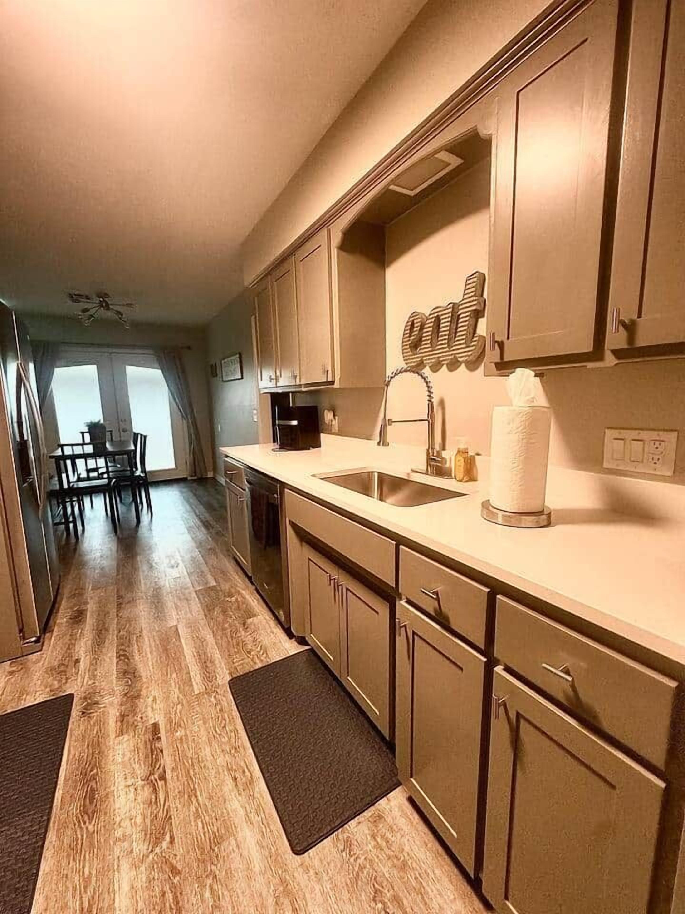 A kitchen with wooden cabinets, a sink, and a dining area with a table and chairs.