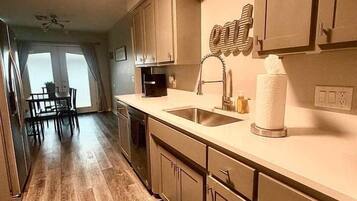 A kitchen with wooden cabinets, a sink, and a dining area with a table and chairs.