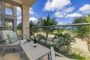 Ein Balkon mit Tisch, zwei Stühlen und einer Weinflasche.