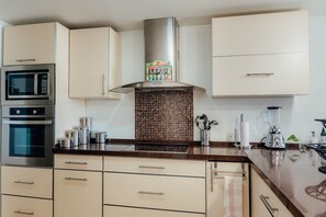 Una cocina moderna con electrodomésticos de acero inoxidable, salpicadero de azulejos y encimera con una licuadora y utensilios.