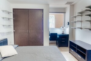 Ein Schlafzimmer mit einem Bett, einem Kleiderschrank, einem Schreibtisch und Regalen.