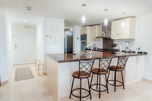 A modern kitchen with a central island, bar stools, and pendant lighting. - Luxury Oasis Retreat Near Eagle Beach 3BR 3BA (Eagle Beach)