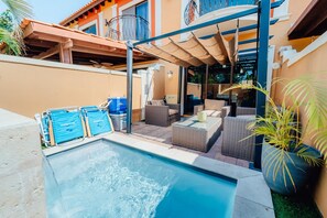 A pool area with a covered seating area, lounge chairs, and a poolside table. - Gold Coast Retreat: 2BR/3BA Townhome, Private Pool (Noord)