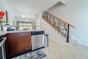 Una cocina moderna con lavavajillas, un armario de madera y un lavamanos de acero inoxidable.