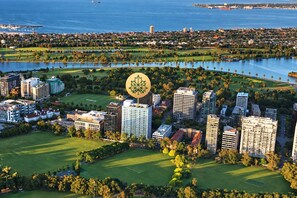 A coastal cityscape with high-rise buildings, a marina, and a golf course. - Luxury 2BR Stay with Pool Gym and Parking (Melbourne)