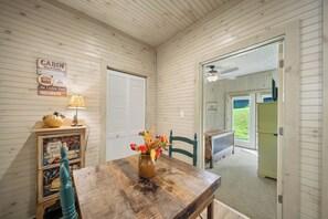 Ein Interieur einer Holzhütte mit einem Holztisch, einer Lampe, einer Vase mit Blumen und einer Wand mit dekorativen Schildern im Hütteurstil.