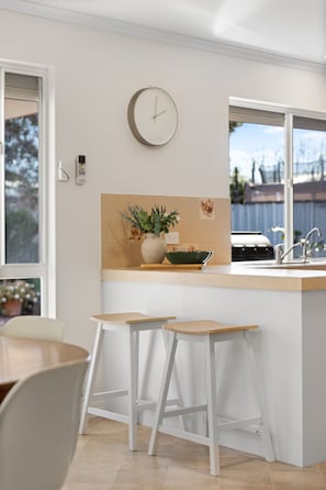 A kitchen with a clock, a window, and a plant on the counter. - Broadstairs—Spacious Beachside Garden Escape (Port Elliot)