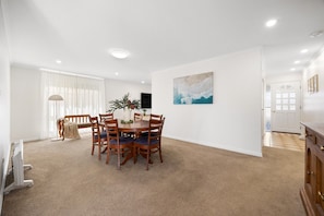 A dining area with a round table, chairs, and a plant on the table. - Broadstairs—Spacious Beachside Garden Escape (Port Elliot)