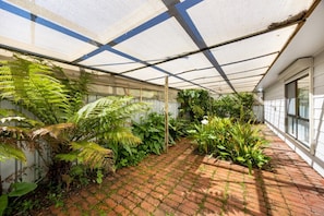 A greenhouse with a variety of plants and a brick pathway. - Broadstairs—Spacious Beachside Garden Escape (Port Elliot)