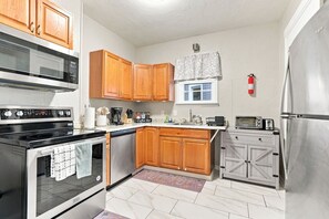 A kitchen with wooden cabinets, a stainless steel refrigerator, a microwave, and a coffee maker. - Beautifully Remodeled 3BR Home Near Niagara Falls! (Niagara Falls)