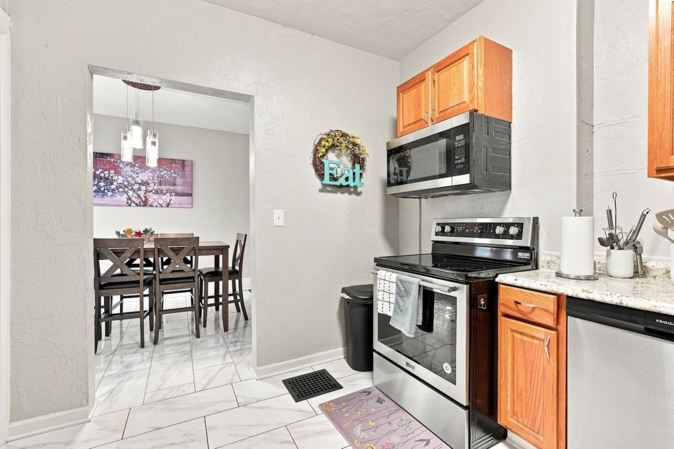 A kitchen with a stove, microwave, and wooden cabinets.
