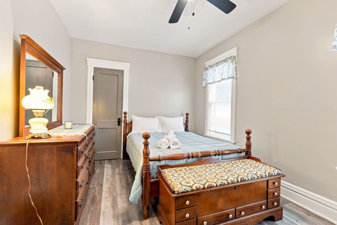 A bedroom with a bed, dresser, mirror, and ceiling fan.