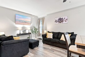 A modern living room with a sofa set, a coffee table, and a painting on the wall. - Beautifully Remodeled 5BR Home Near Niagara Falls! (Niagara Falls)