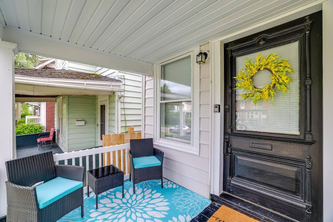 A porch with wicker furniture and a blue patterned rug.