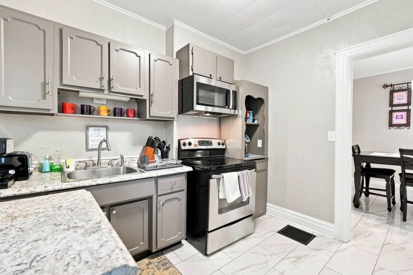 A kitchen with grey cabinets, a microwave, a stove, and a sink.