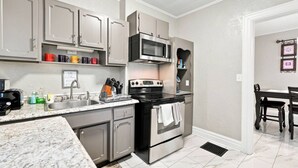 A kitchen with grey cabinets, a microwave, a stove, and a sink. - Beautifully Remodeled 4BR Home Near Niagara Falls! (Niagara Falls)