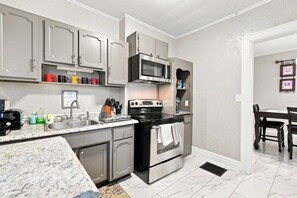 A kitchen with grey cabinets, a microwave, a stove, and a sink. - Beautifully Remodeled 4BR Home Near Niagara Falls! (Niagara Falls)