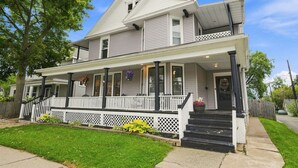 A two-story house with a front porch, a covered entryway, and a visible front yard. - Beautifully Remodeled 4BR Home Near Niagara Falls! (Niagara Falls)