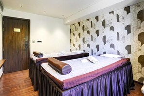 A hotel room with two beds, a wooden door, and a patterned wall. - Palette City Formerly Emerald Guestimony (Pune)
