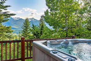 A hot tub with a wooden deck and a mountain view. - Mountain Escape. Sauna & Soak. (Columbia-Shuswap)