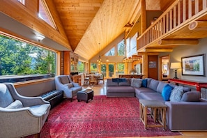 A spacious living area with a large red patterned rug, a sofa, and a dining table. - Mountain Escape. Sauna & Soak. (Columbia-Shuswap)