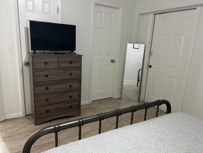 Un dormitorio con cama, cómoda, televisor y espejo.