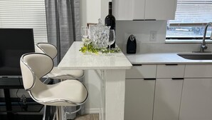 Une cuisine moderne avec un îlot central, des tabourets de bar, une bouteille de vin et un évier.