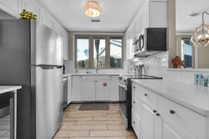A modern kitchen with white cabinets, stainless steel appliances, and a large window providing natural light. - Seascape 3 BD/2 BA condo- 3 min walk to beach! Miramar Beach Destin (Miramar Beach)