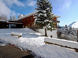 Ein Skiverleih mit einem Holzbau und einem mit Schnee bedeckten Baum.