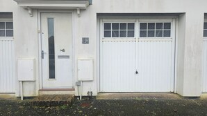 A building with a white door, a garage door, and a small mailbox. - House Sleeps 4 with Parking (Newquay)