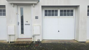 Um edifício com porta branca, porta de garagem e uma caixa de correio pequena.