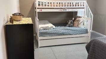 Un lit superposé avec une petite table et un réfrigérateur, dans une pièce dont le sol est recouvert d’un motif à motifs.