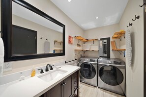 A compact laundry room with a washing machine, a dryer, and a sink. - Beech Mountain Cabin with Retro Mountain Charm (Beech Mountain)