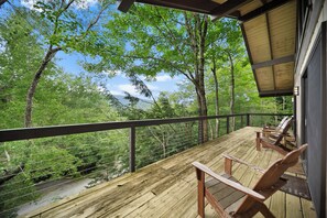 A wooden deck with a railing, overlooking a forested area with trees and a clear sky. - Beech Mountain Cabin with Retro Mountain Charm (Beech Mountain)