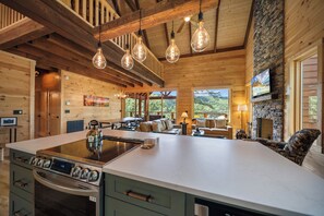 A spacious kitchen with a central island, wooden beams, and hanging light fixtures. - Charming Mountain Retreat Near Banner Elk (Banner Elk)