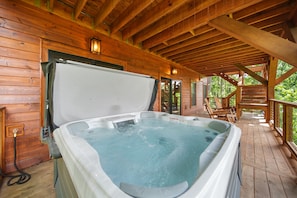 Eine Holzhütte mit Whirlpool auf einer Terrasse.