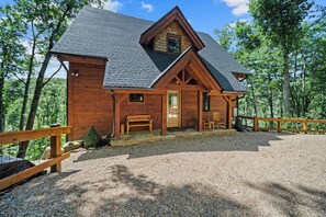 A wooden cabin with a sloped roof, a front porch with a bench, and a gravel driveway. - Charming Mountain Retreat Near Banner Elk (Banner Elk)