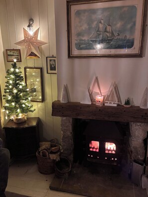 A cozy room with a lit fireplace, a decorated Christmas tree, and nautical-themed decorations.