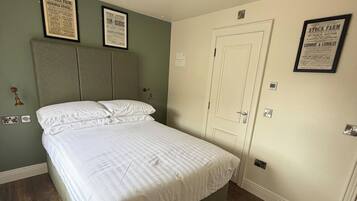 A bedroom with a bed, a door, and framed posters on the wall.